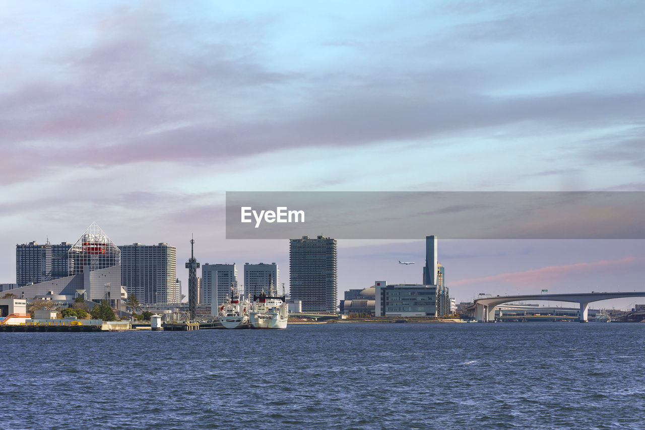 Boats moored at harumi passenger terminal on tokyo bay in front of ariake island at sunset.