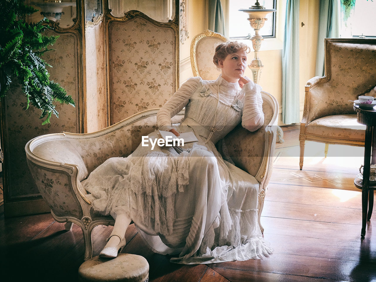 YOUNG WOMAN SITTING ON CHAIR IN HOME