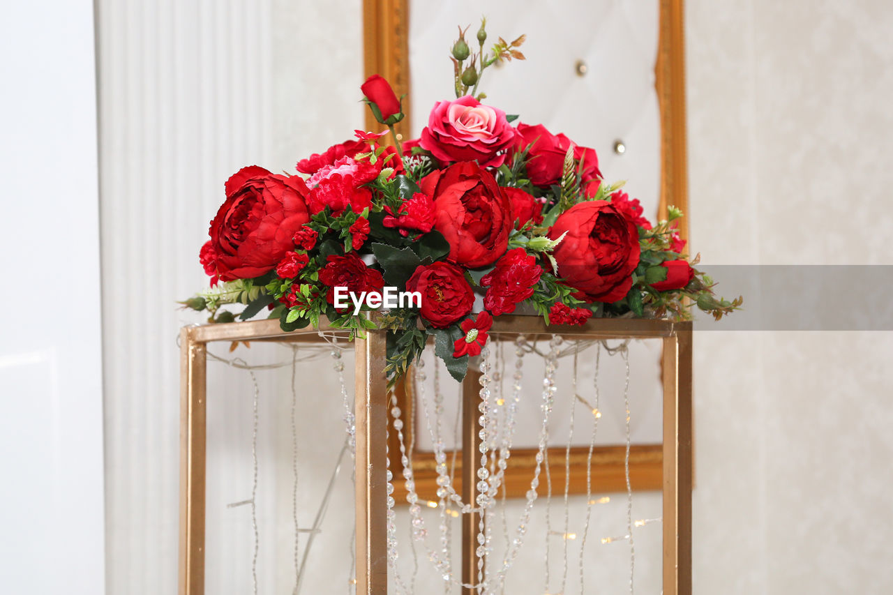 Composition of artificial flowers decorated with beads and garland, decoration of the banquet hall.