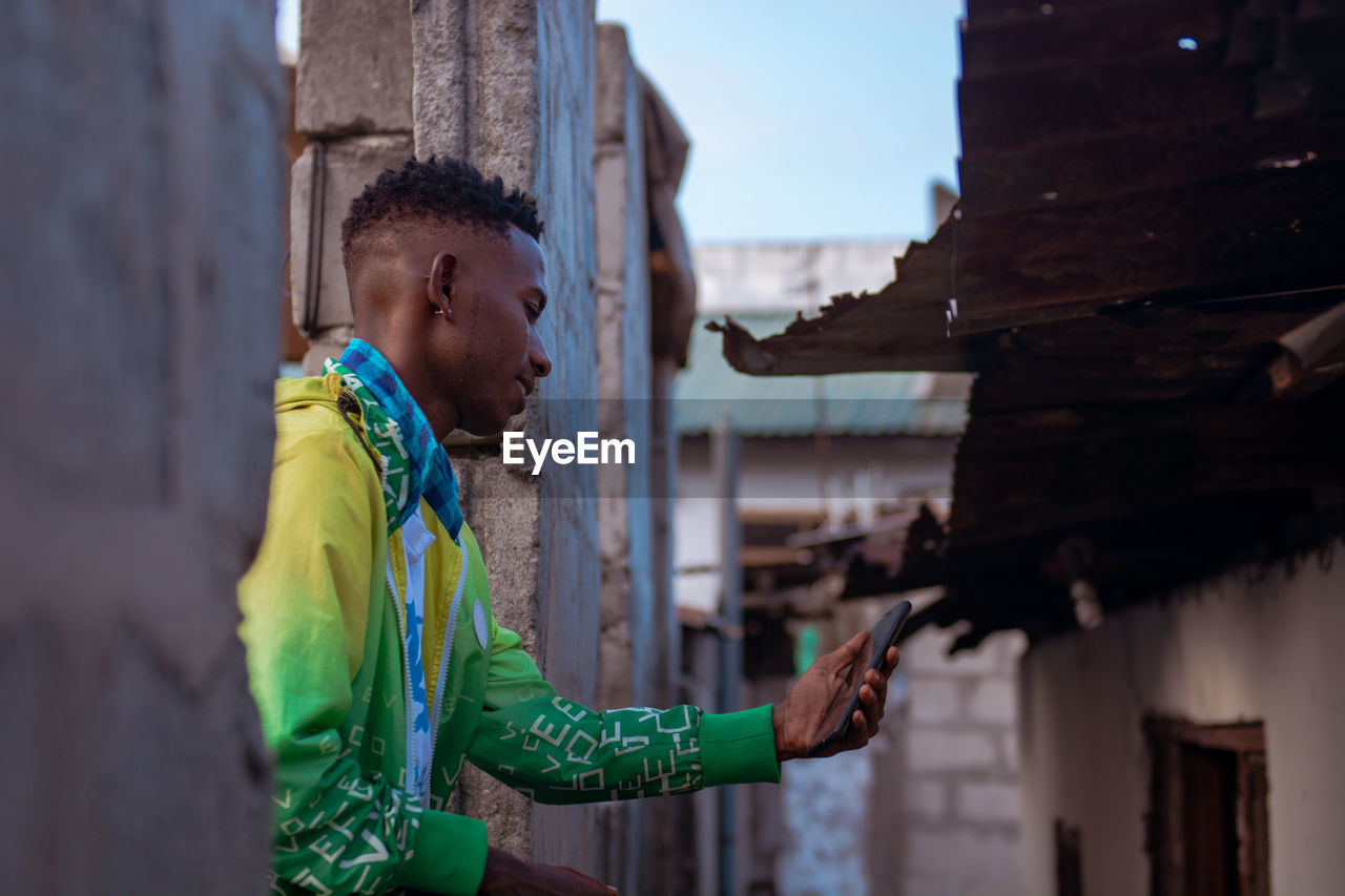 Portrait of young man looking using a mobile phone in the slums