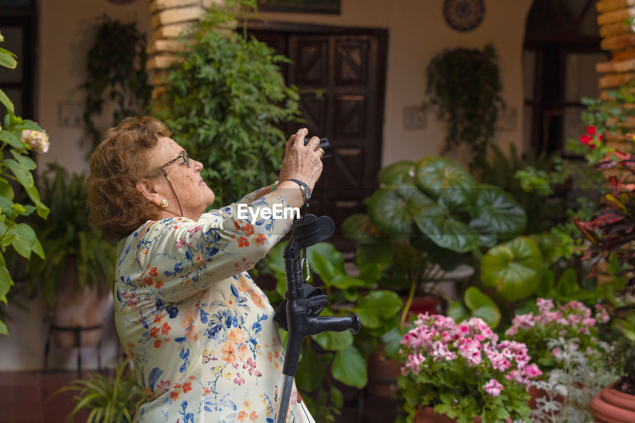 SIDE VIEW OF WOMAN HOLDING FLOWERS AT NIGHT