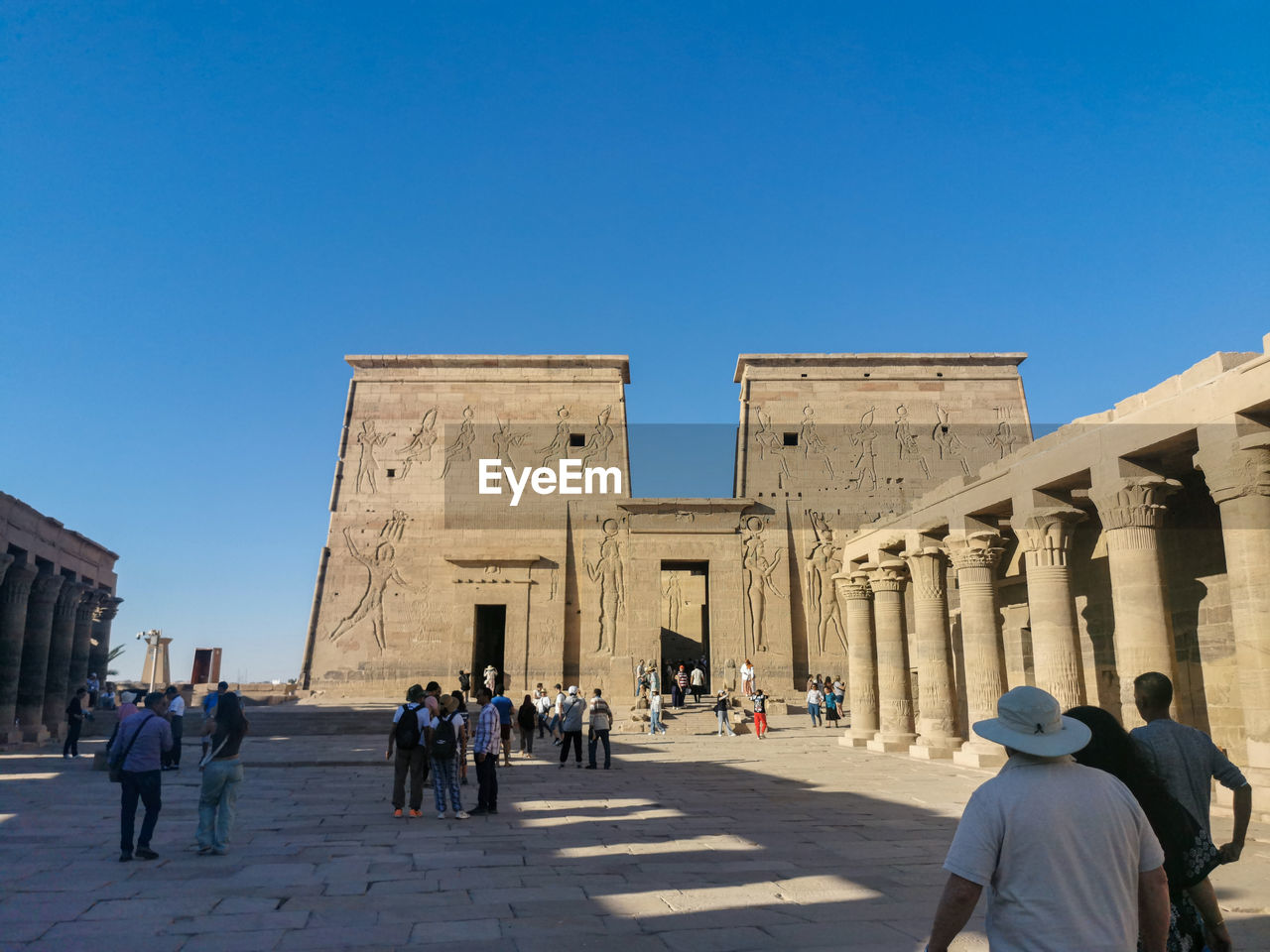 architecture, group of people, history, the past, travel destinations, built structure, travel, large group of people, sky, tourism, crowd, clear sky, landmark, building exterior, city, men, ancient, blue, adult, nature, tourist, sunny, ancient history, women, religion, lifestyles, monument, architectural column, day, temple, sunlight, walking, outdoors, building, leisure activity, belief