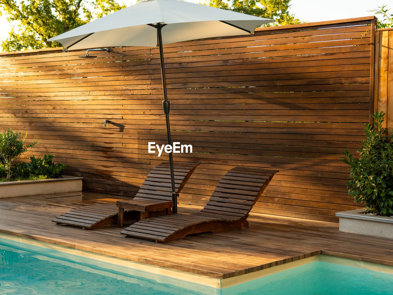 swimming pool, water, nature, luxury, relaxation, wealth, architecture, wood, summer, tourist resort, vacation, trip, tranquility, plant, holiday, tree, backyard, no people, deck, travel destinations, poolside, outdoor structure, tranquil scene, built structure, outdoors, day, lounge chair, sunlight, building exterior, house, chair, tropical climate, lifestyles, front or back yard, beauty in nature, health spa, idyllic, hotel, travel, building, patio, sky, furniture, leisure activity, seat, absence, residential district, comfortable, luxury hotel, food and drink
