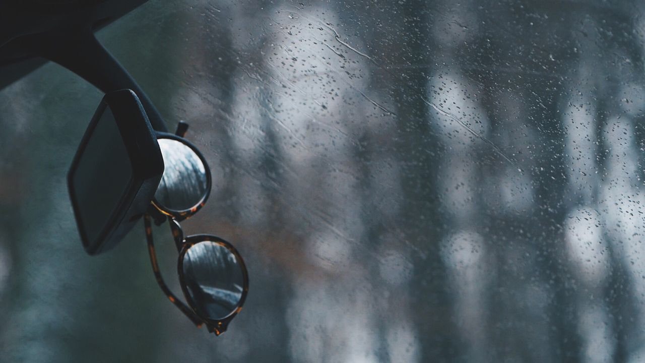 Close-up of sunglasses with raindrops on rainy day