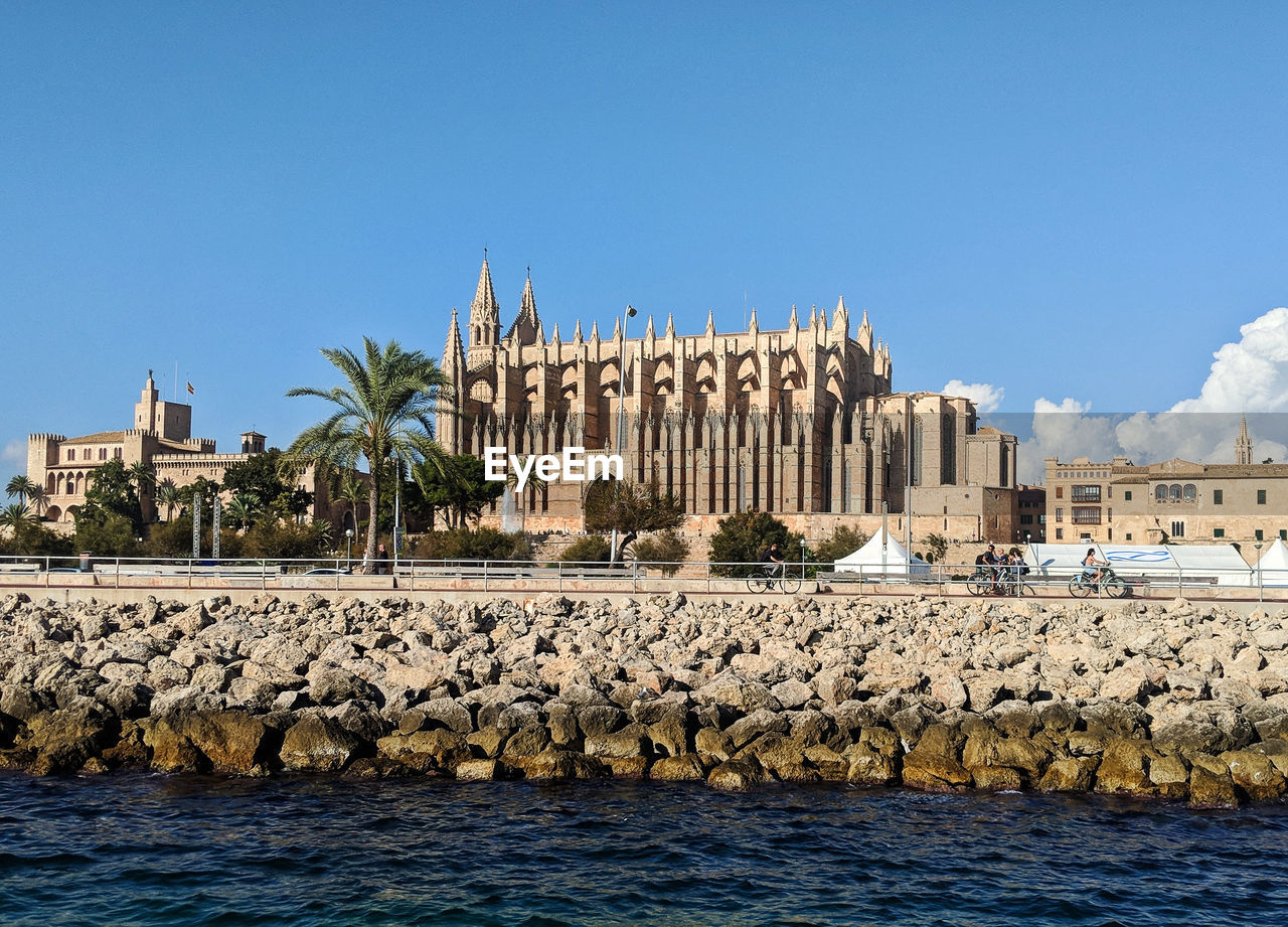 View of building by sea against clear blue sky