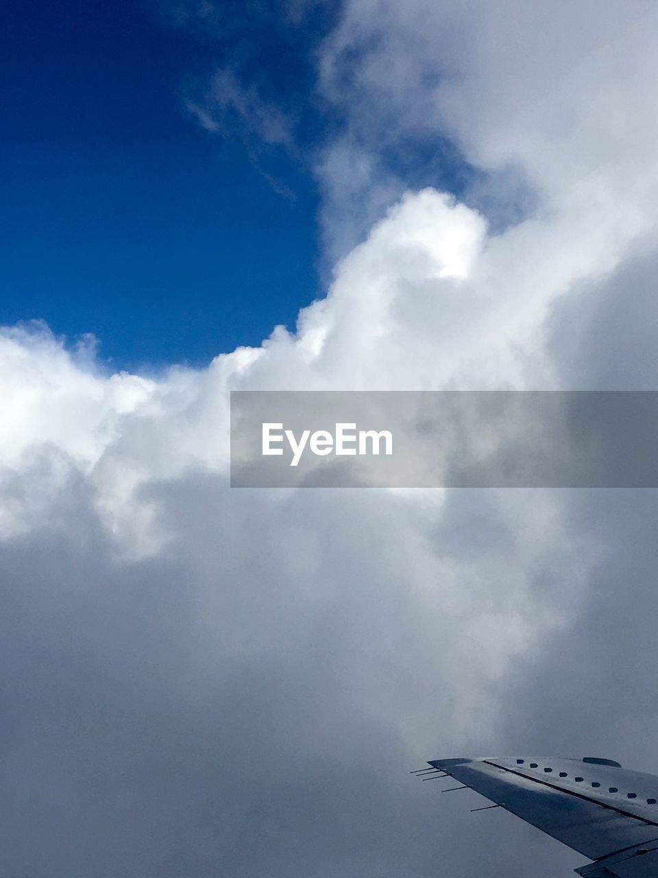 LOW ANGLE VIEW OF AIRPLANE FLYING OVER CLOUDS