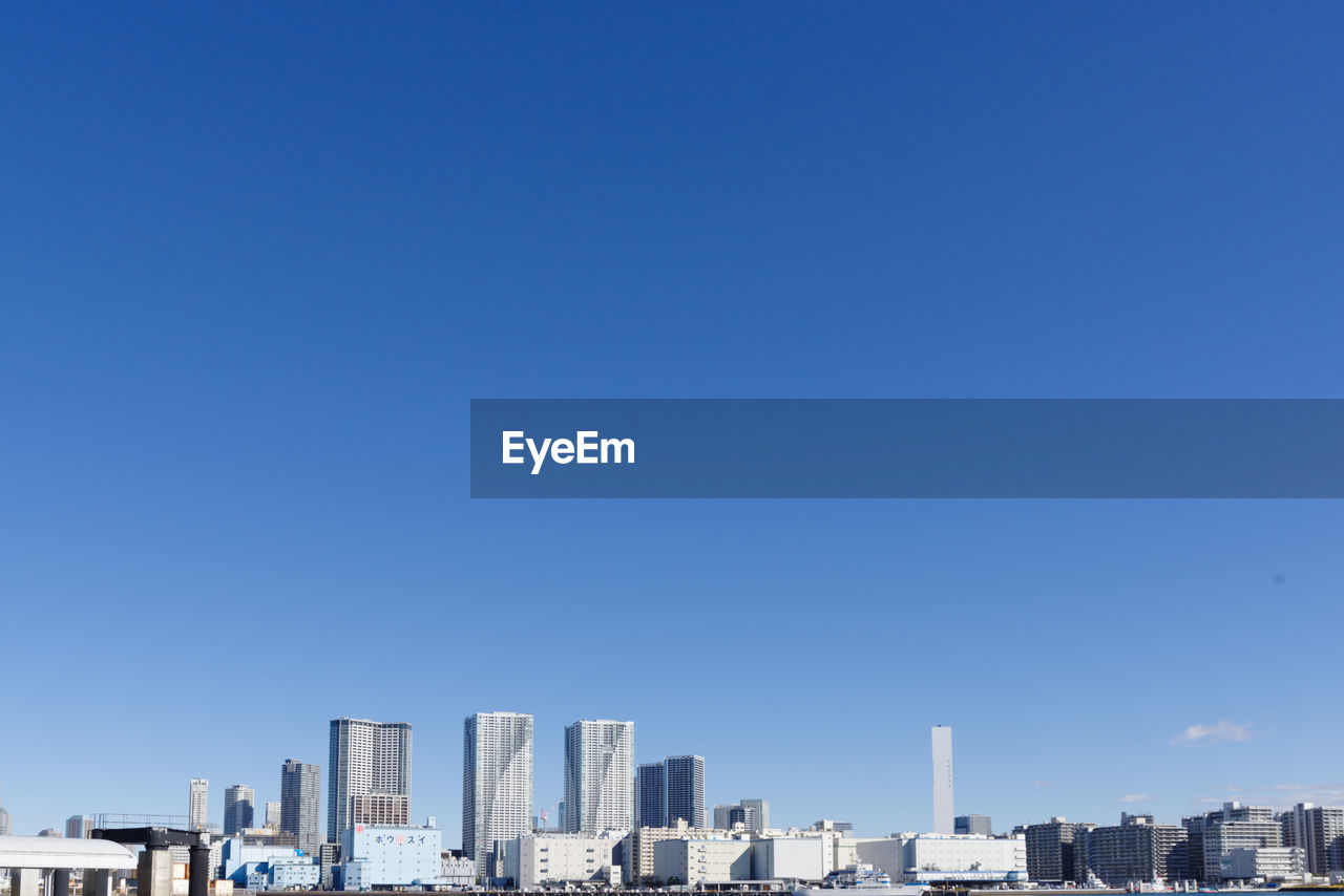 Modern buildings in city against clear blue sky