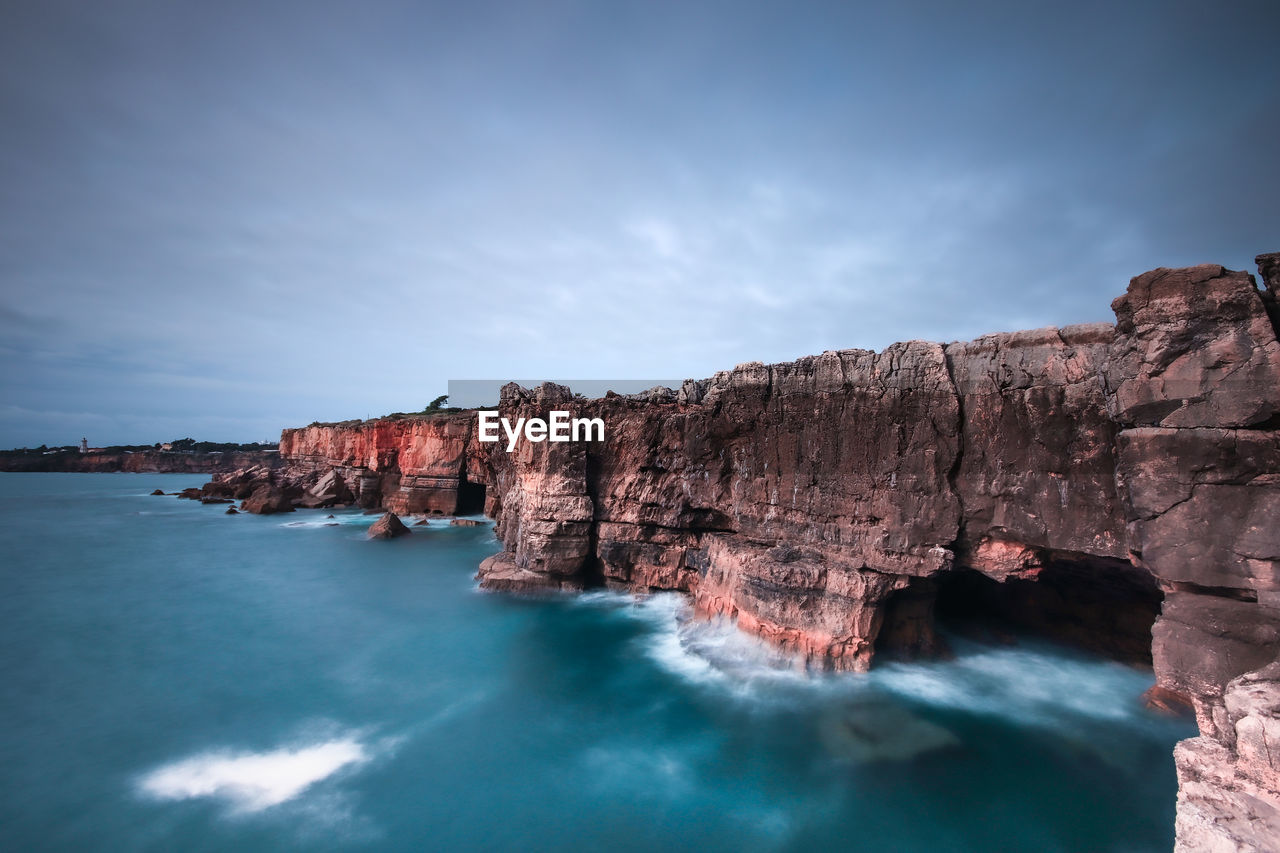 SCENIC VIEW OF SEA BY ROCK FORMATION AGAINST SKY