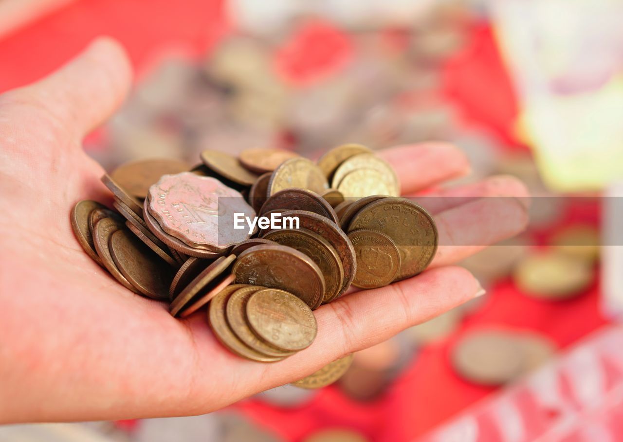 CLOSE-UP OF HUMAN HAND HOLDING COIN