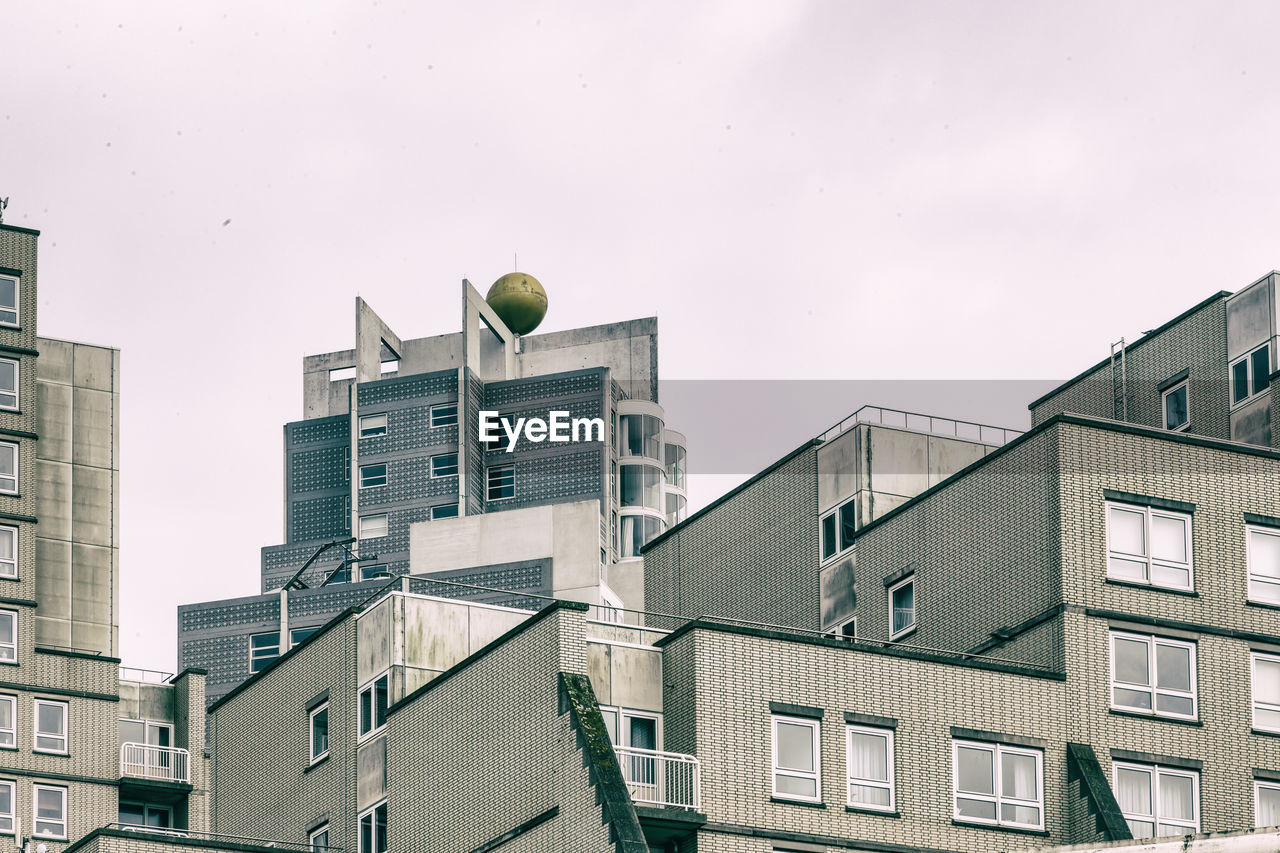 Low angle view of modern buildings against cloudy sky