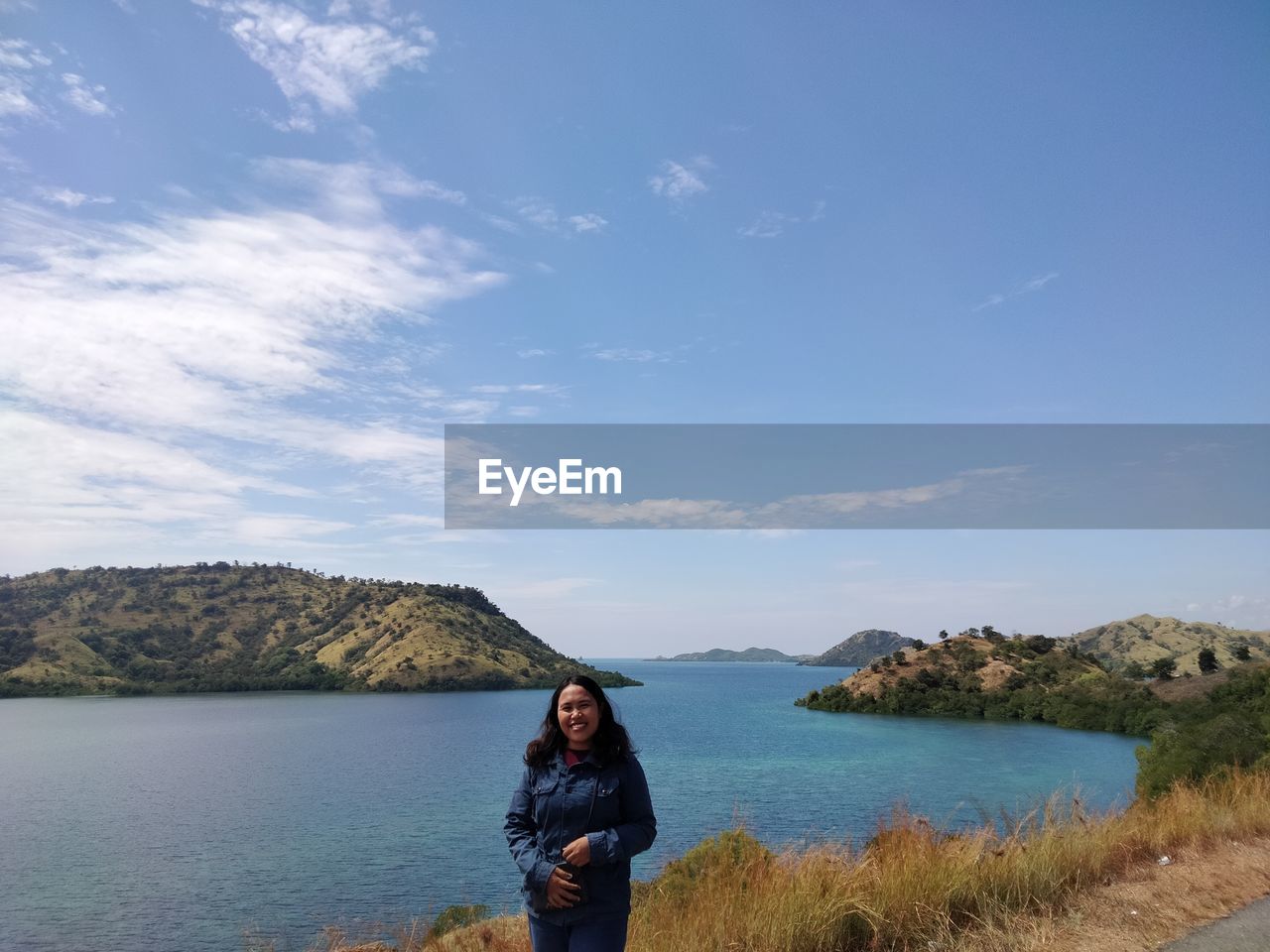 Rear view of woman standing by lake against sky