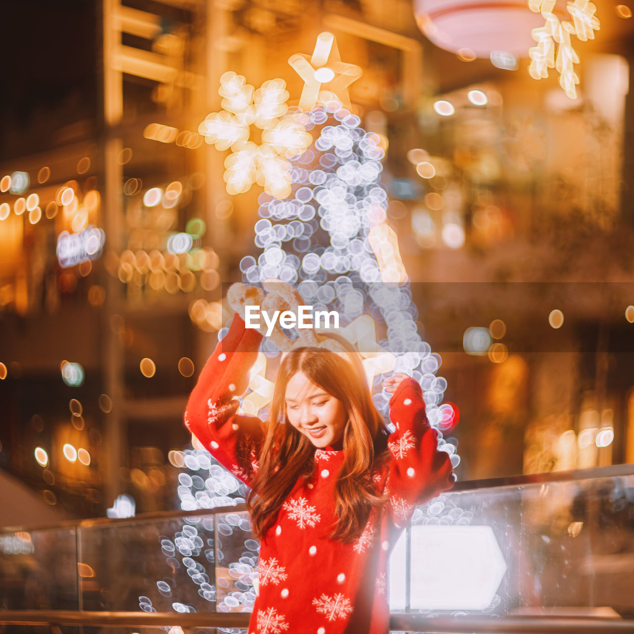 portrait of smiling young woman standing against illuminated christmas tree