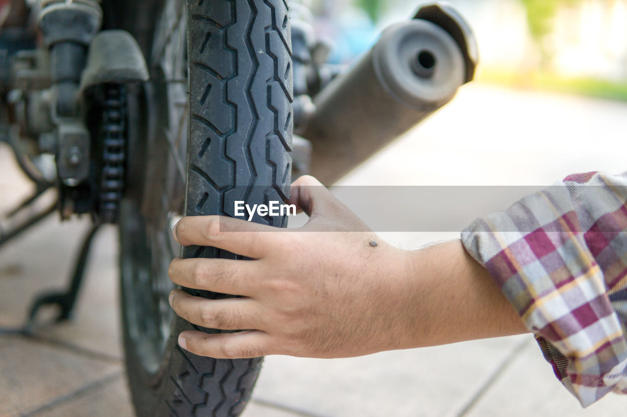 tire, wheel, one person, automotive tire, adult, hand, men, bicycle, occupation, working, transportation, day, focus on foreground, outdoors, holding, close-up, auto part, mode of transportation, mechanic