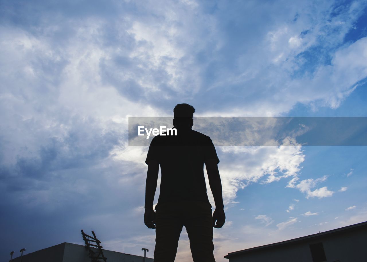 SILHOUETTE OF MAN STANDING AGAINST SKY