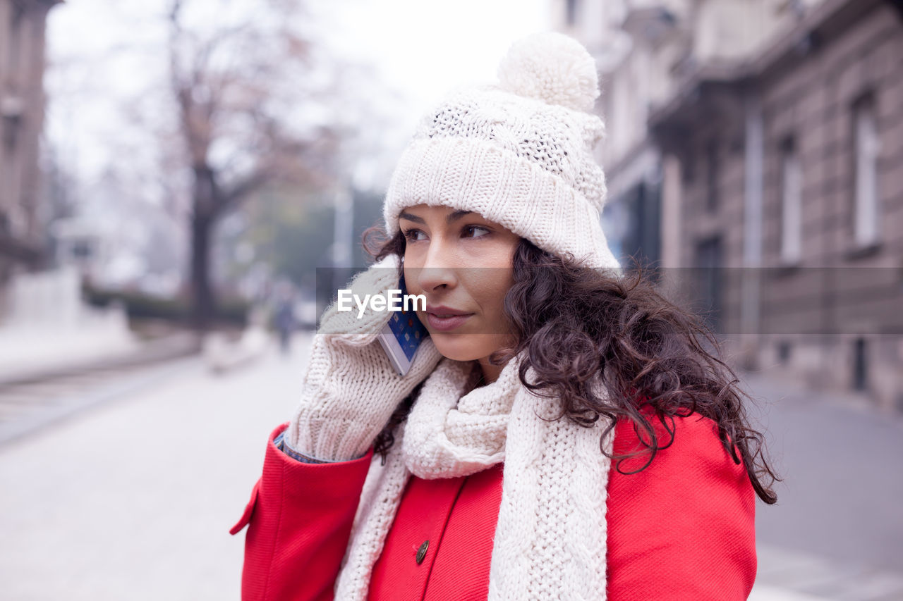 Young woman talking on smart phone while standing in city