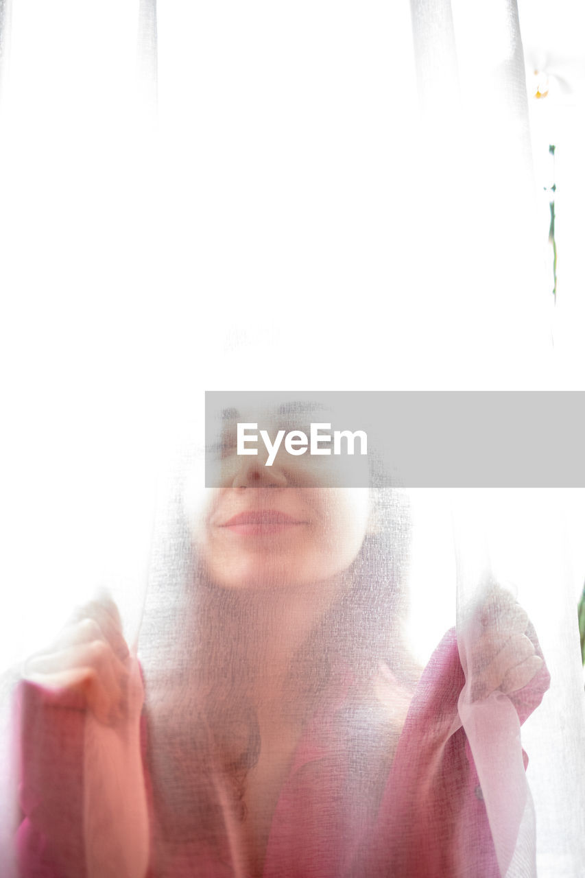 Portrait of woman against sky seen through window