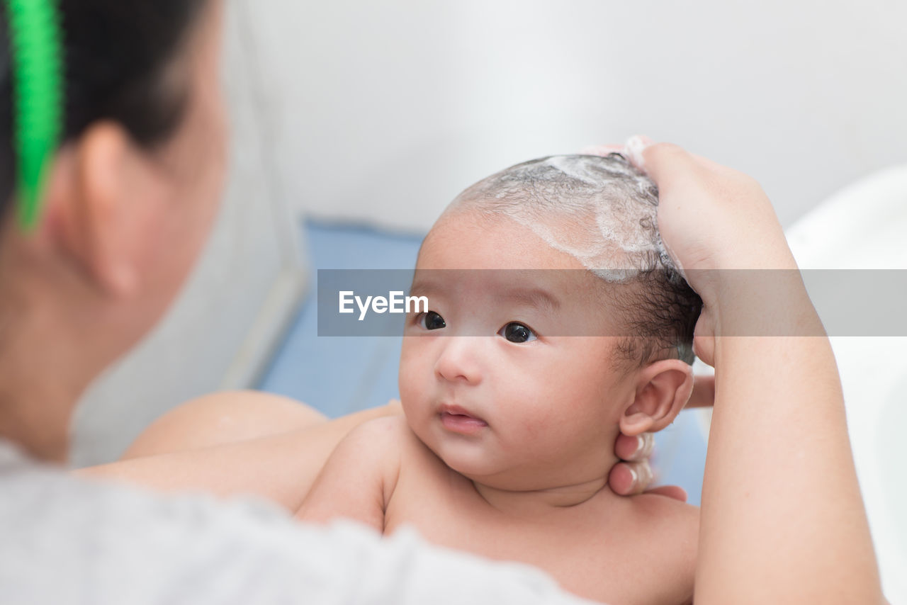 High angle view of mother bathing baby boy at home