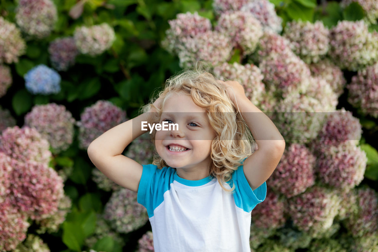 Smiling girl standing against pink flowering plants