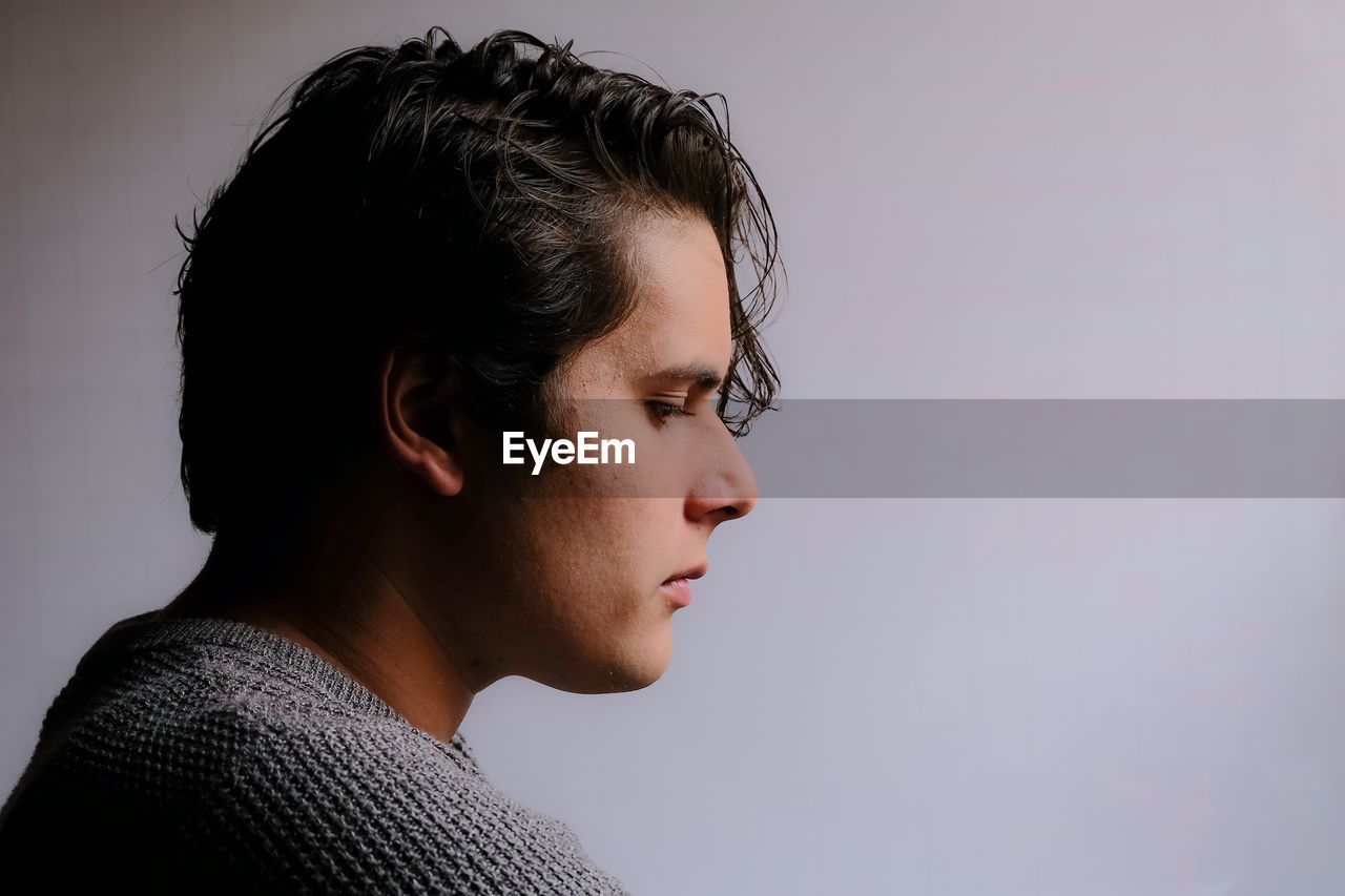 Thoughtful young man looking away against white background