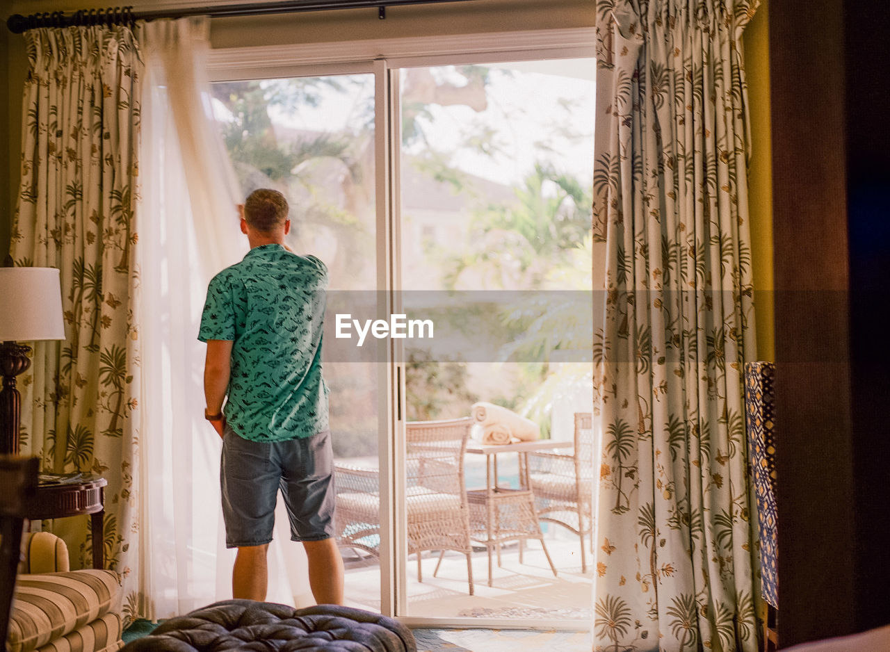 Man standing by window at home