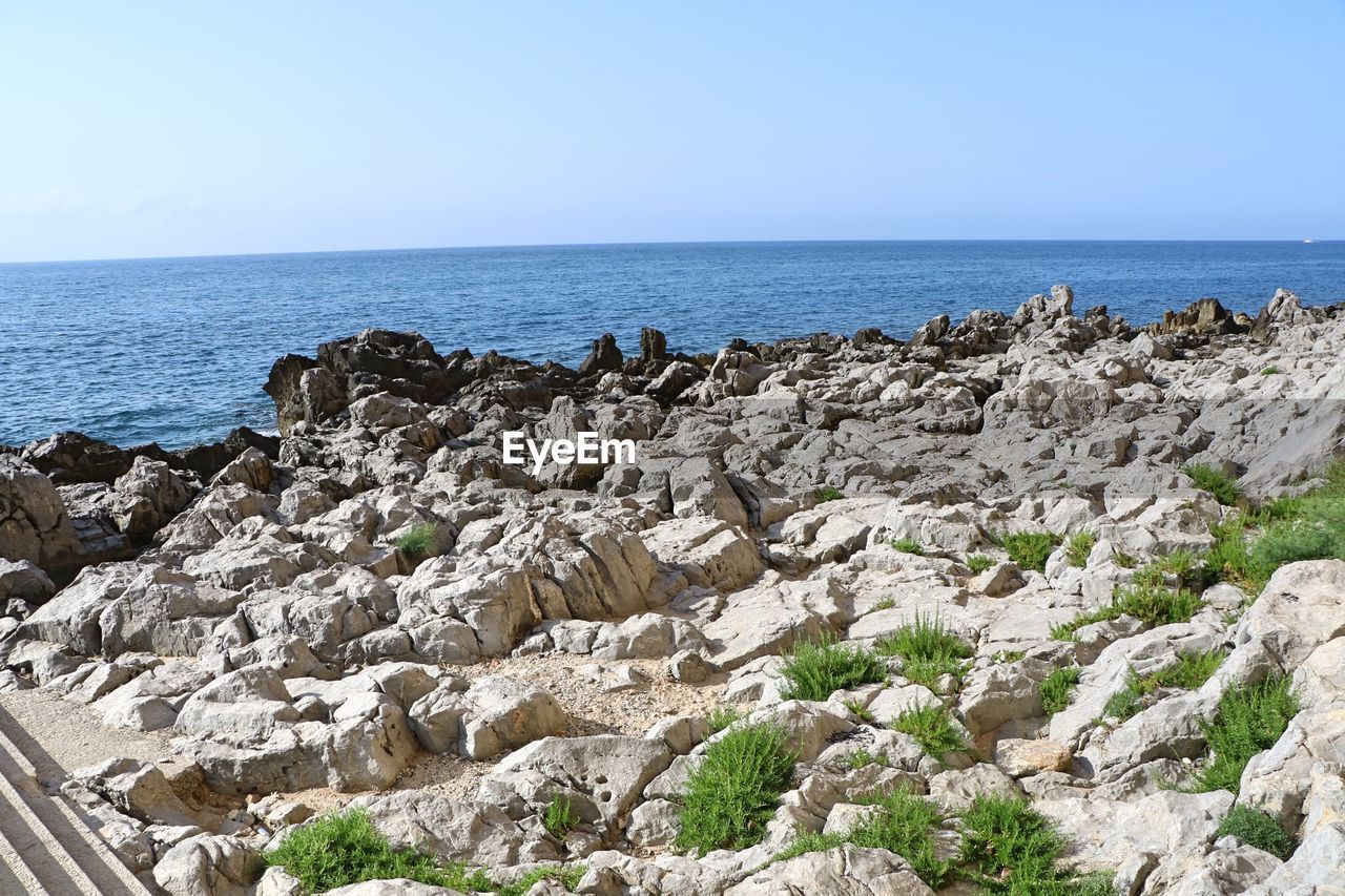 SCENIC VIEW OF ROCKY BEACH AGAINST SKY