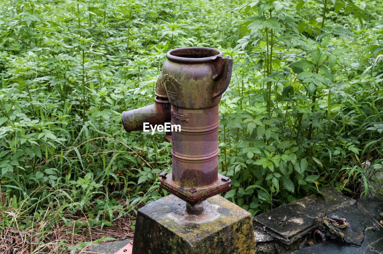 Close-up of a well pump against grasses