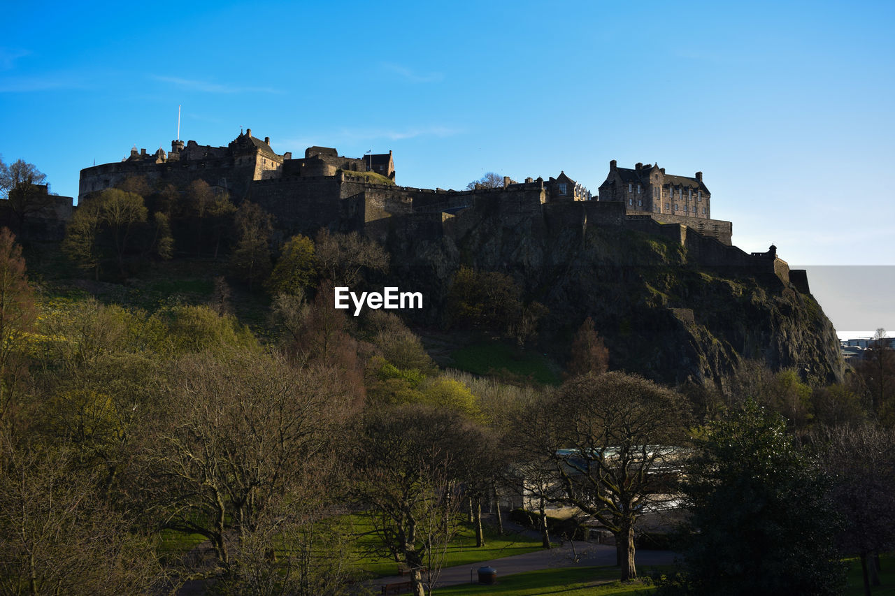 Low angle view of edinburgh castle on mountain against blue sky