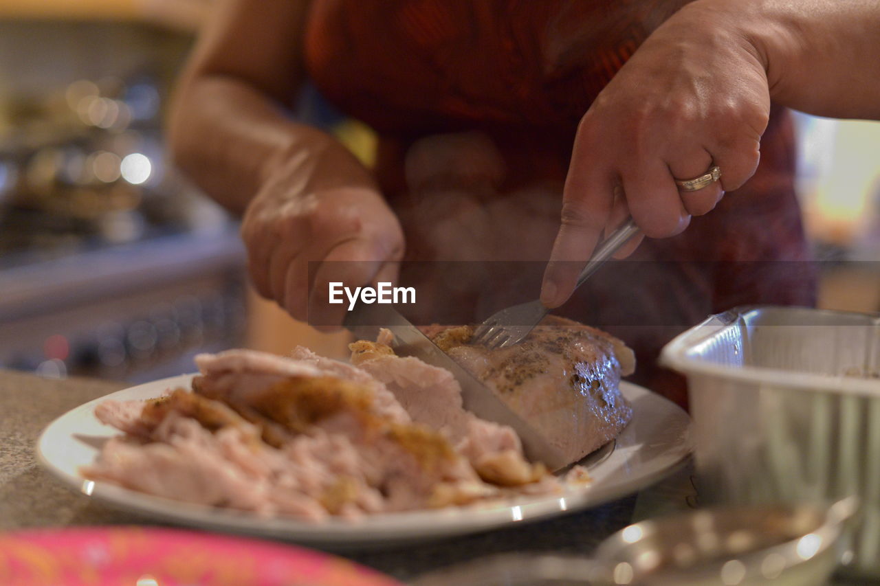 Close-up of woman chopping meat in table