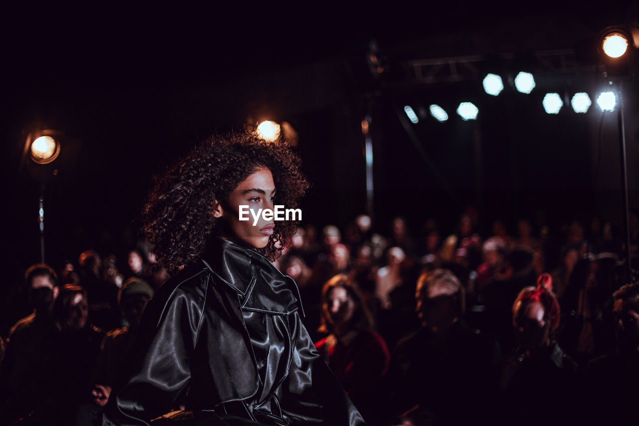 YOUNG WOMAN LOOKING AT CONCERT