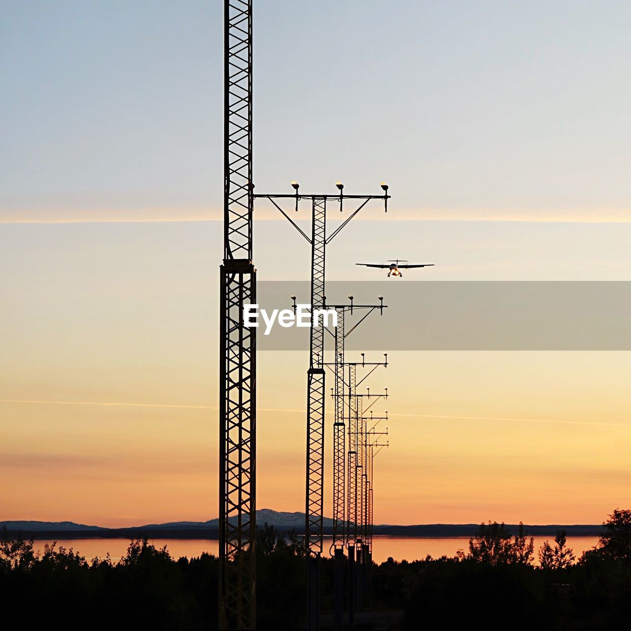 Low angle view of silhouette electricity pylon against sky during sunset