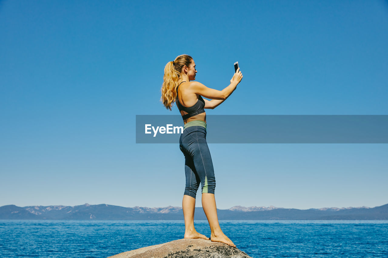 Young woman taking a picture of lake tahoe.