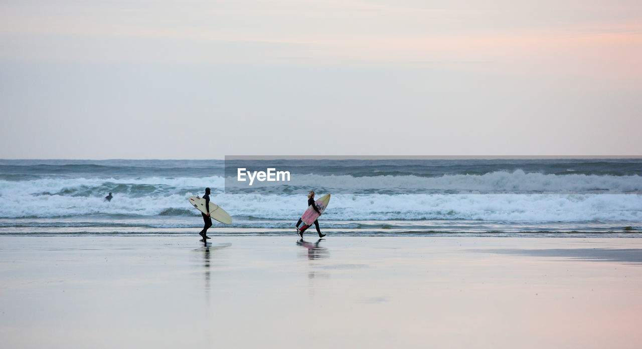 MEN ON BEACH AGAINST SEA