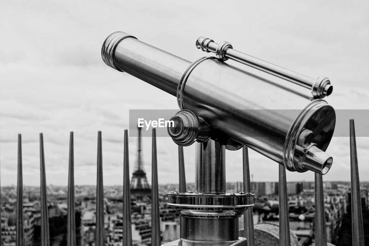 Telescope in city against sky