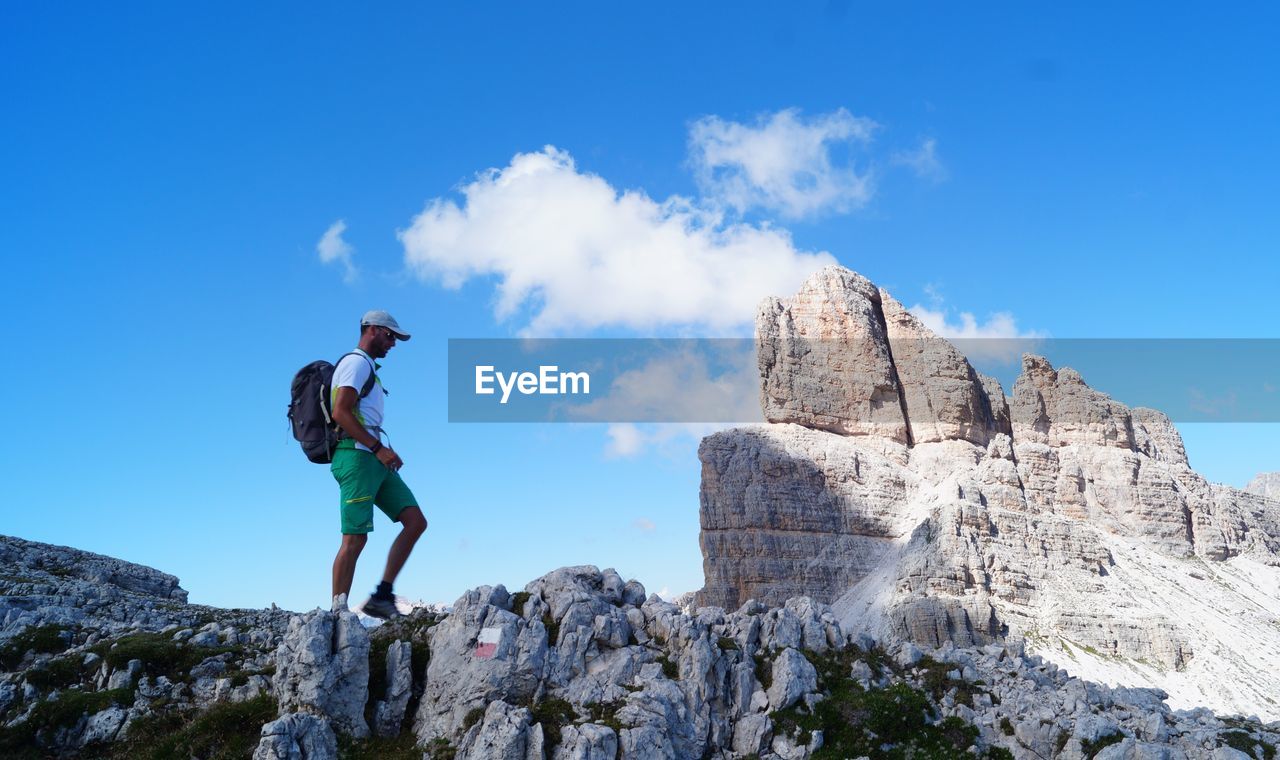 LOW ANGLE VIEW OF MAN STANDING ON ROCK