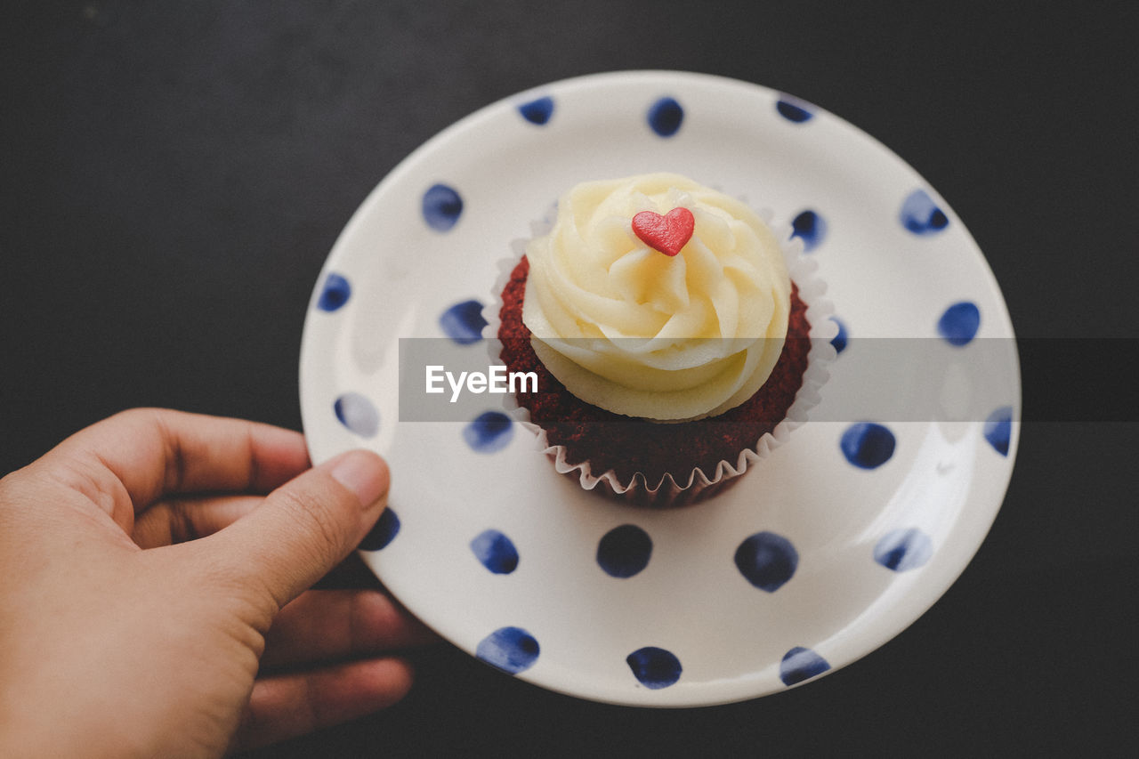 Cropped image of hand holding cupcake plate