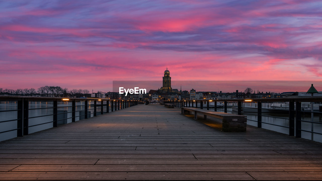 View of bridge over river against buildings at sunset