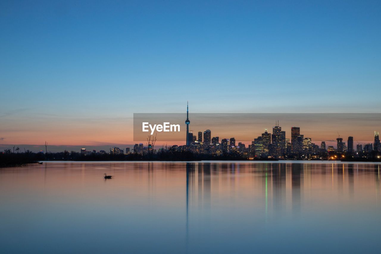 Reflection of buildings in lake during sunset