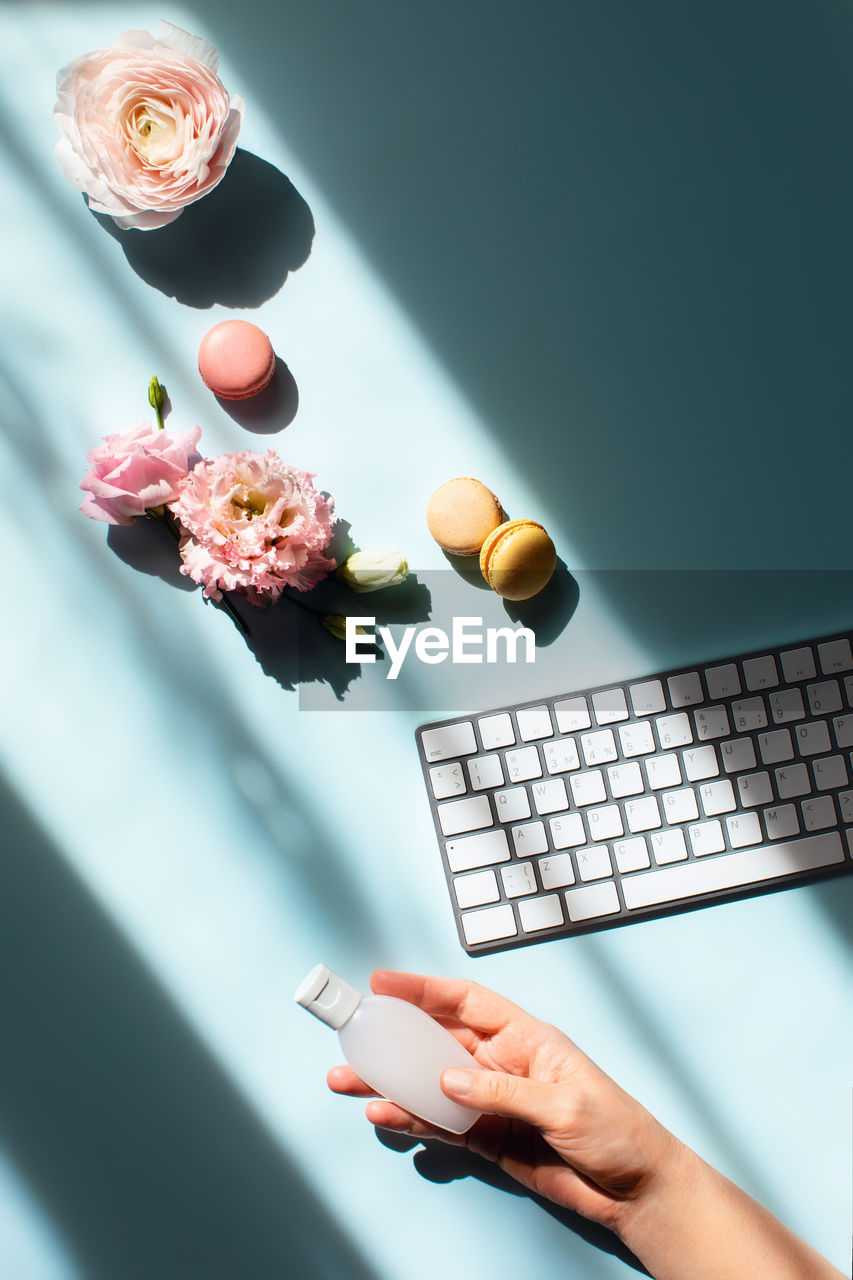 Flowers and macaroons in sunlight and with a sanitizer on a women hand. 