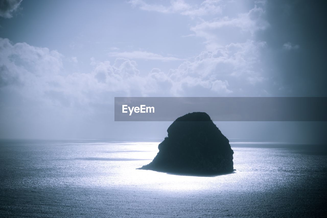 Silhouette rock in sea against sky