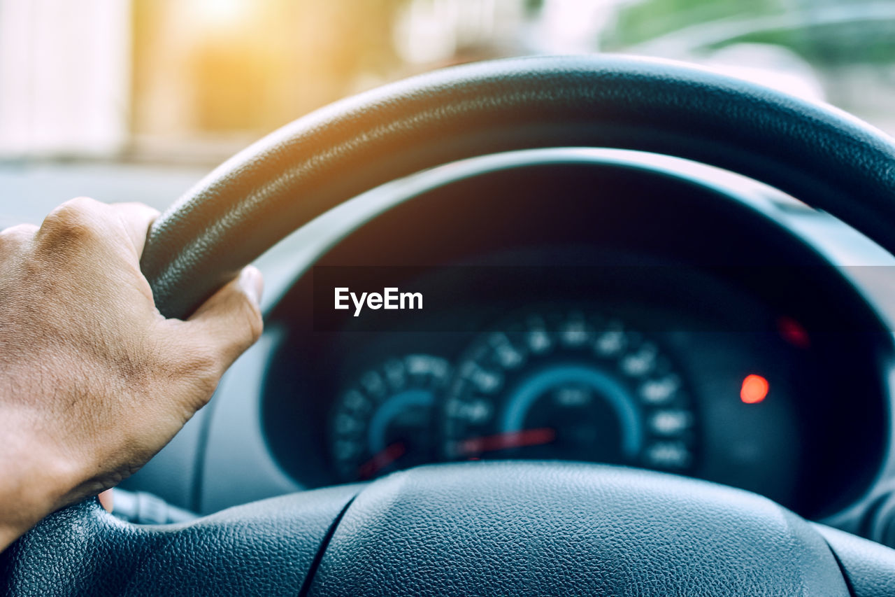 Cropped hand of man driving car