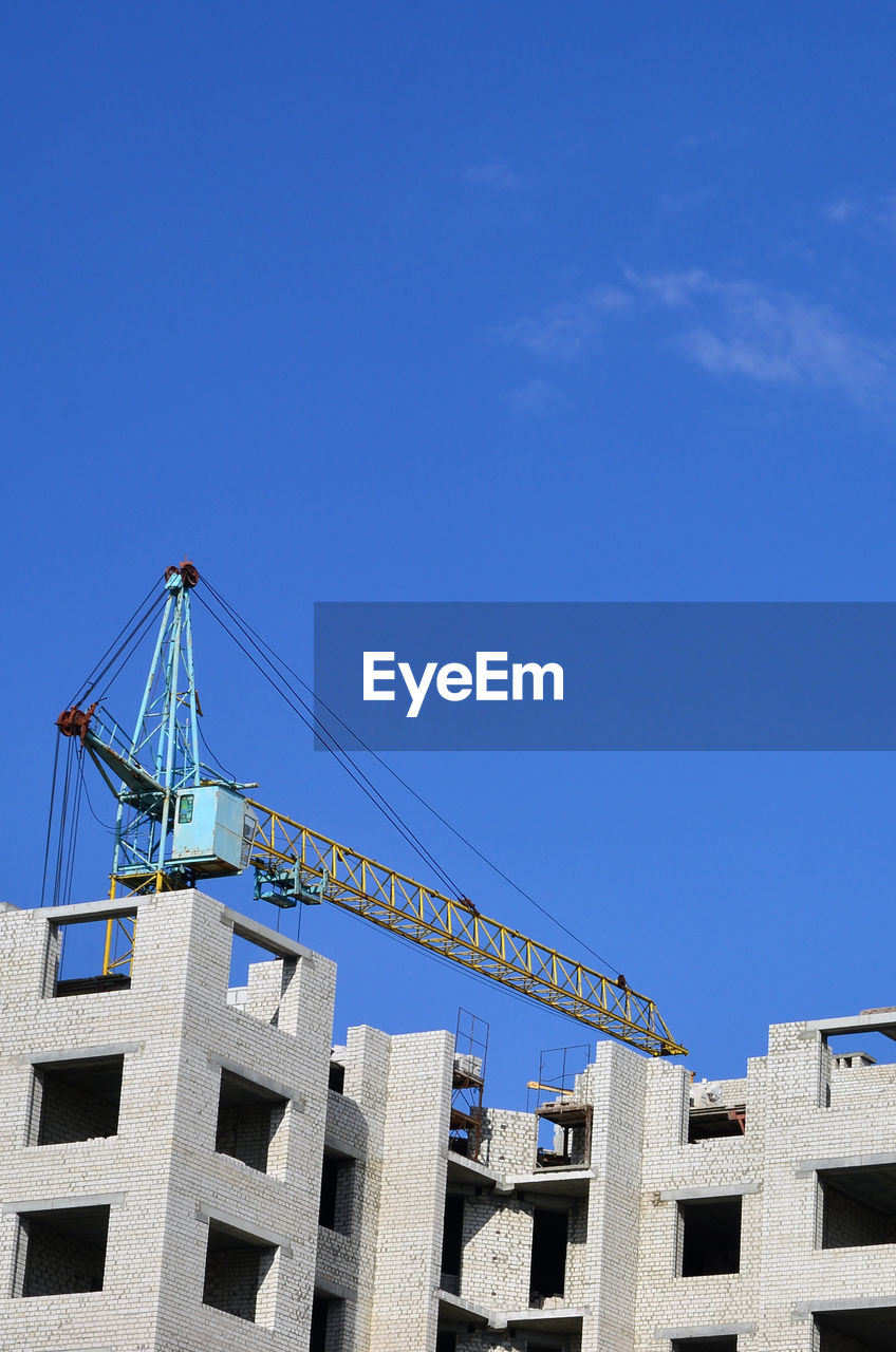 LOW ANGLE VIEW OF CRANE AGAINST BUILDING