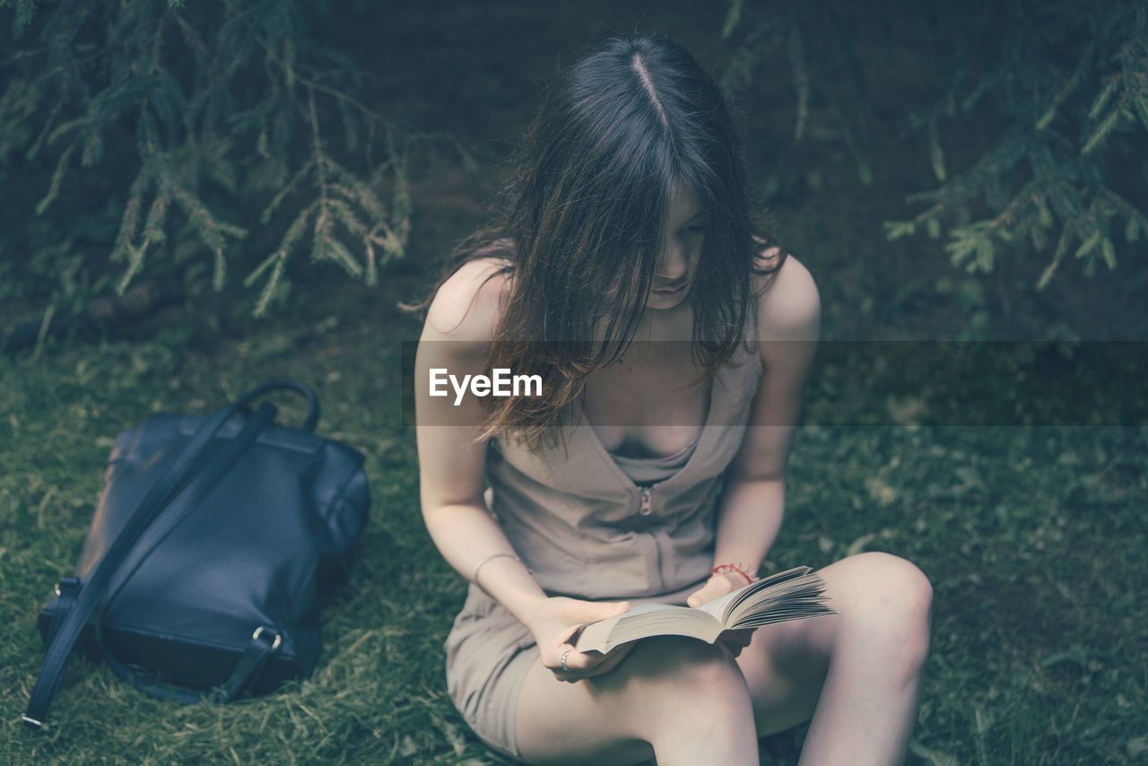 MIDSECTION OF WOMAN SITTING ON GRASS