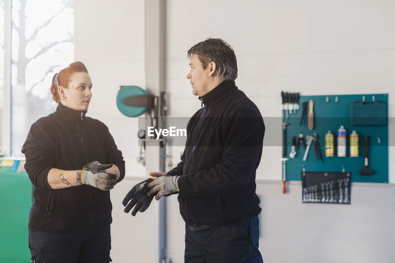 Male and female mechanics wearing gloves in auto repair shop