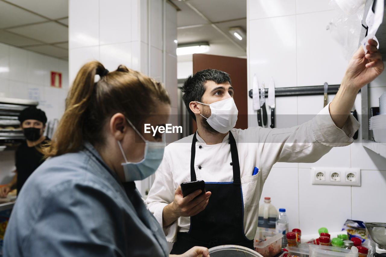 Male and female chef working in commercial kitchen during covid-19