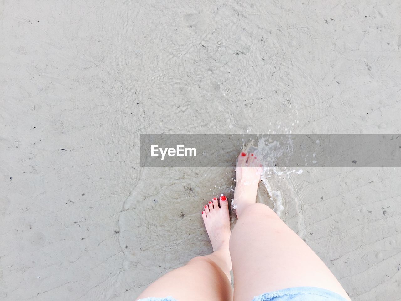 Low section of woman standing at beach