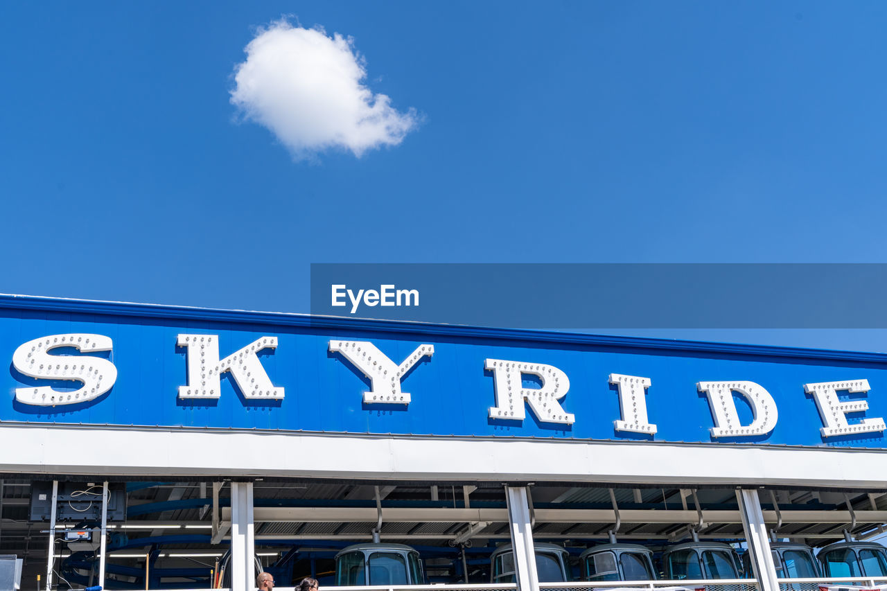 LOW ANGLE VIEW OF SIGNS AGAINST BLUE SKY