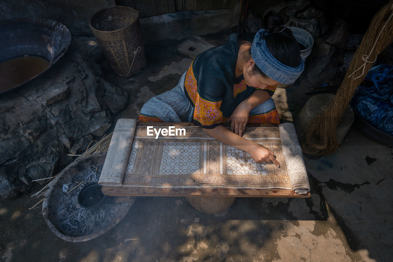 HIGH ANGLE VIEW OF MAN WORKING ON METAL