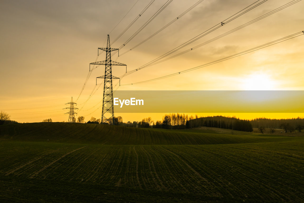 High voltage electricity pole and transmission power lines at sunset