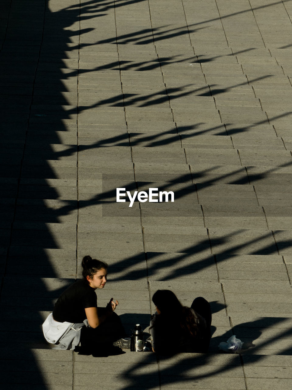 High angle view of friends sitting on steps during sunny day