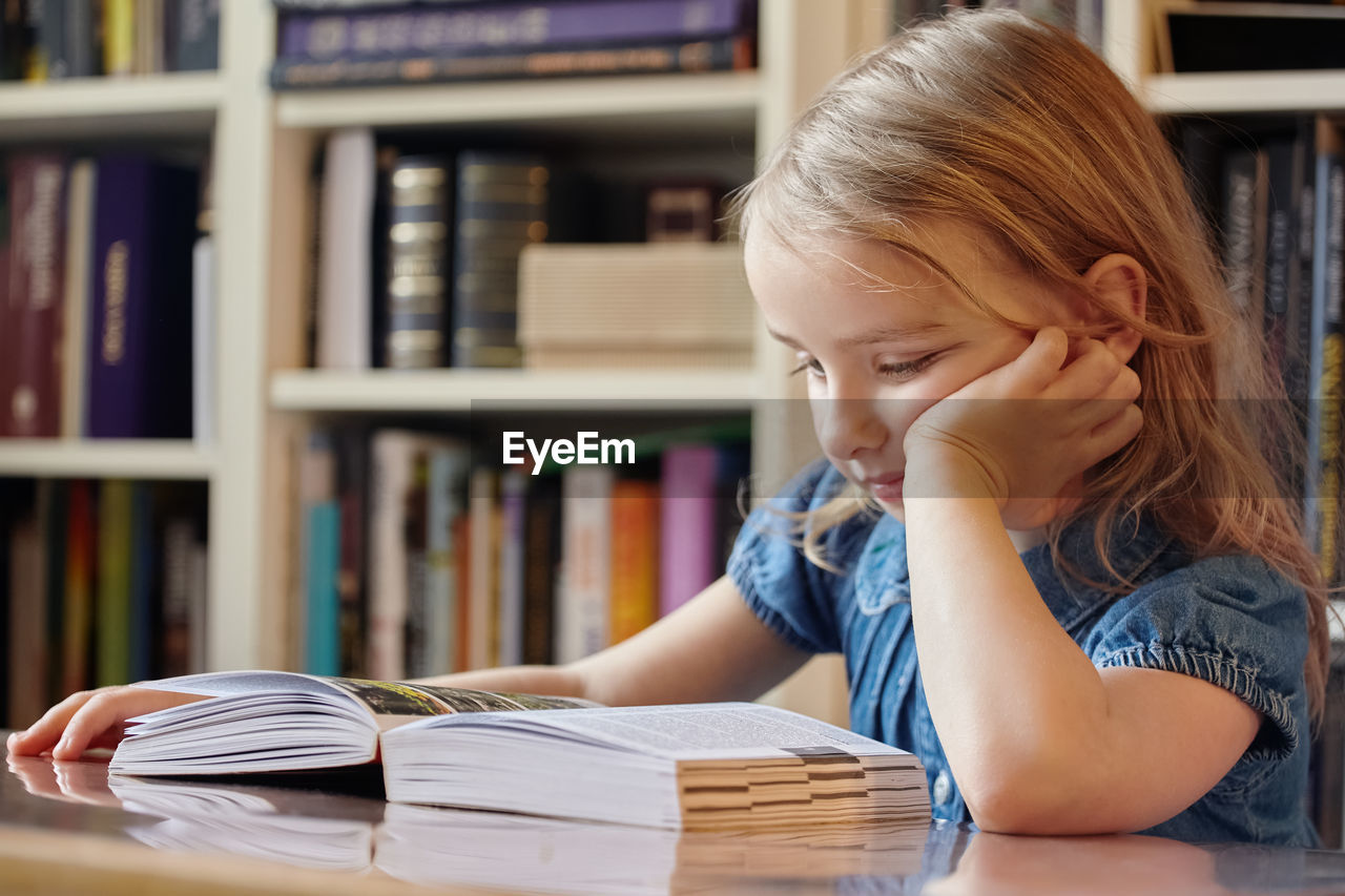 Girl reading book in library